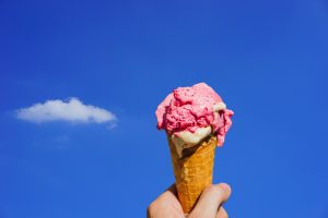 Hand holding pink ice cream cone to the sky